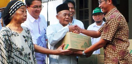 Ahmad Muhibbuddin didampingi oleh (kedua kiri) Yudi Yozardi dari AHM menyerahkan paket sembako Ramadhan kepada warga 