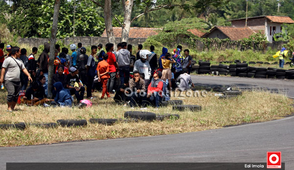 penonton dengan santainya duduk di sisi lintasan tikungan