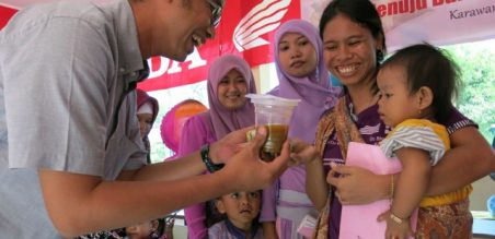 Ahmad Muhibbuddin menyerahkan PMT bagi salah seorang anak balita dalam peringatan bulan gizi nasional 2015 yang diadakan oleh AHM di balai desa Tepas Sahate, Desa Kalihurip, Jawa Barat 