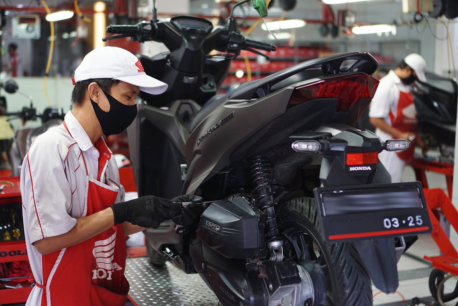 Mekanik sepeda motor Honda sedang melakukan servis sepeda motor milik Konsumen